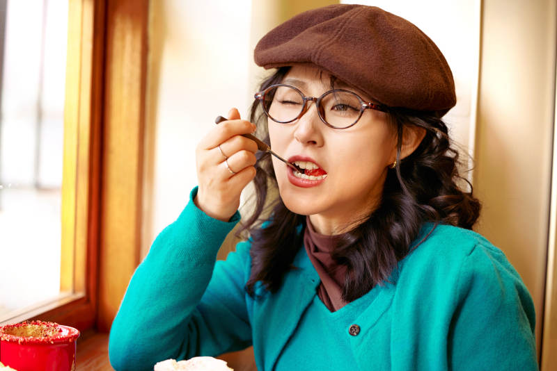 冬日午后坐在咖啡店吃蛋糕喝咖啡的亚洲美女