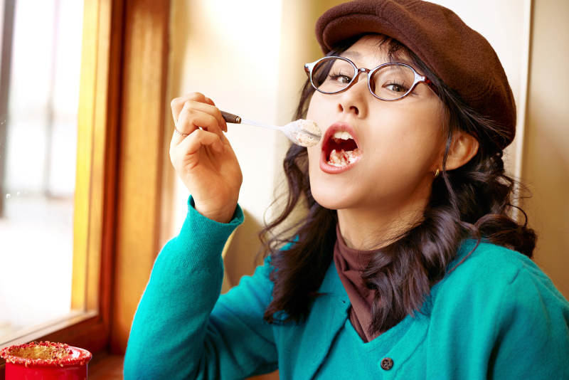 冬日午后坐在咖啡店吃蛋糕喝咖啡的亚洲美女