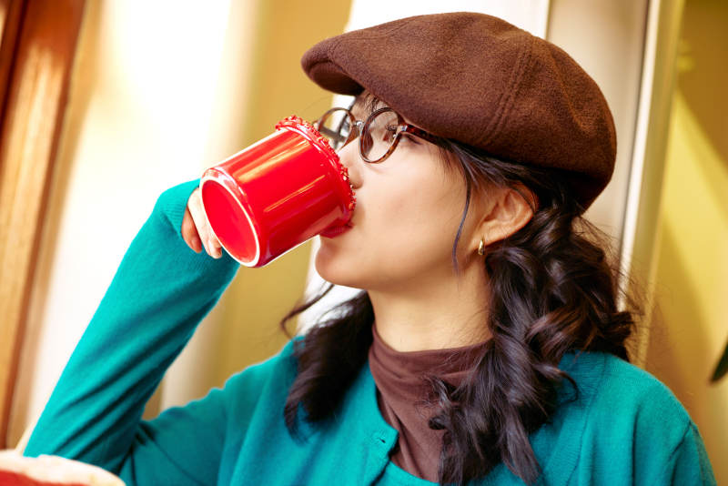 冬日午后坐在咖啡店吃蛋糕喝咖啡的亚洲美女