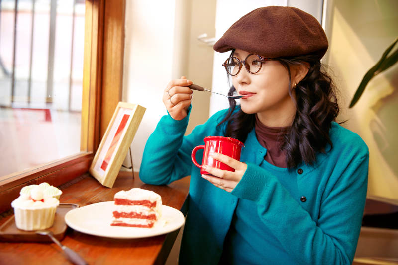 冬日午后坐在咖啡店吃蛋糕喝咖啡的亚洲美女