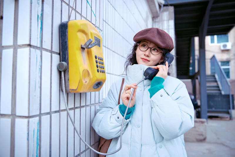 在老旧社区院落回拨打IC卡电话的美女