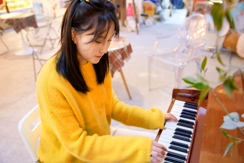 在咖啡店演奏钢琴的东方美女