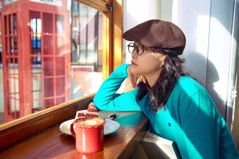 冬日午后坐在咖啡店吃蛋糕喝咖啡的亚洲美女