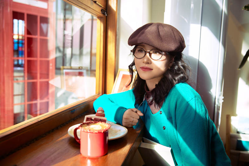 冬日午后坐在咖啡店吃蛋糕喝咖啡的亚洲美女