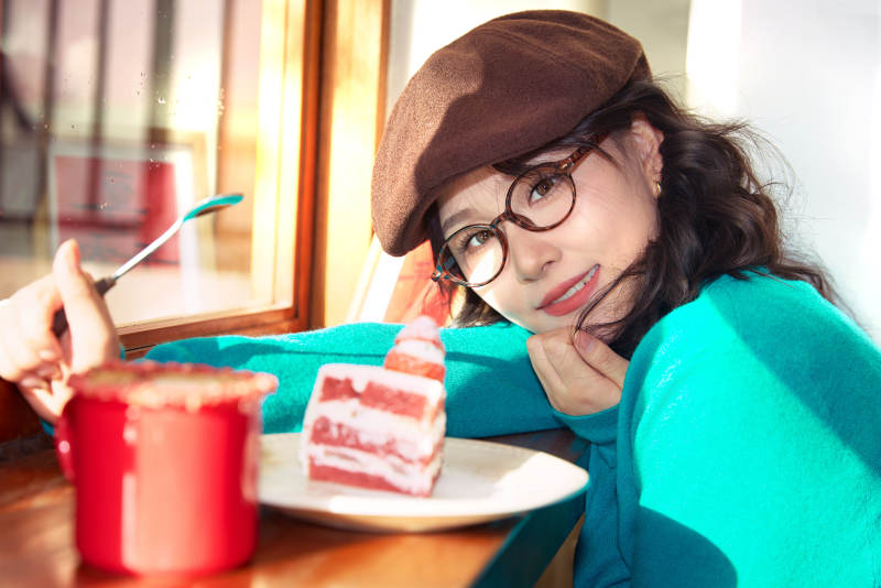 冬日午后坐在咖啡店吃蛋糕喝咖啡的亚洲美女