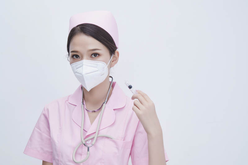 穿护士服戴听诊器口罩手执针筒的年轻女护士