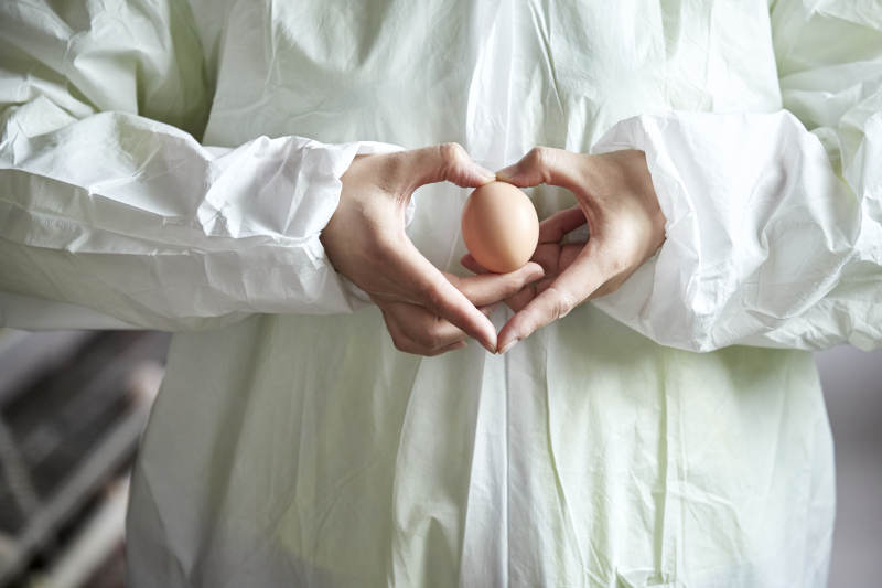 身穿防护服展示油鸡蛋的女性饲养员