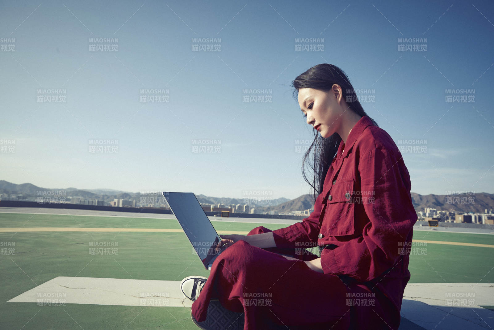 亚洲商务年轻女性在楼顶停机坪使用电脑办公