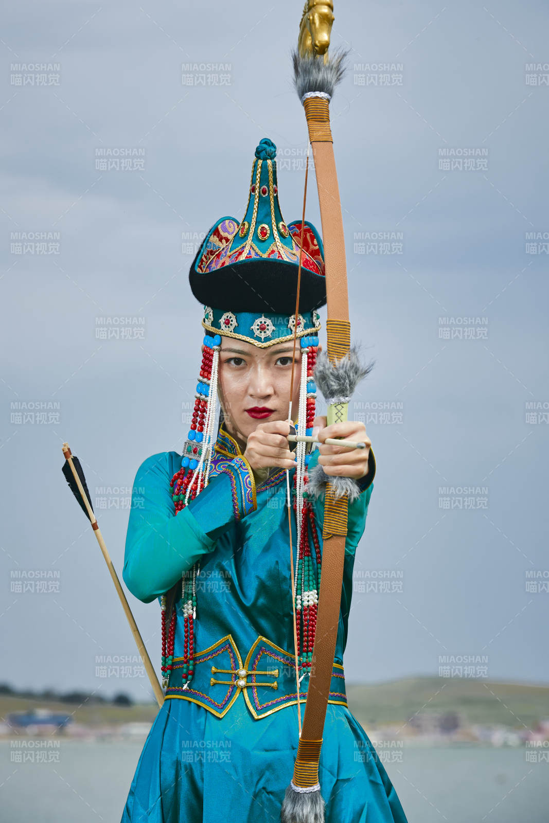 草原湖畔身穿蒙古族飾手持弓箭的蒙族少女