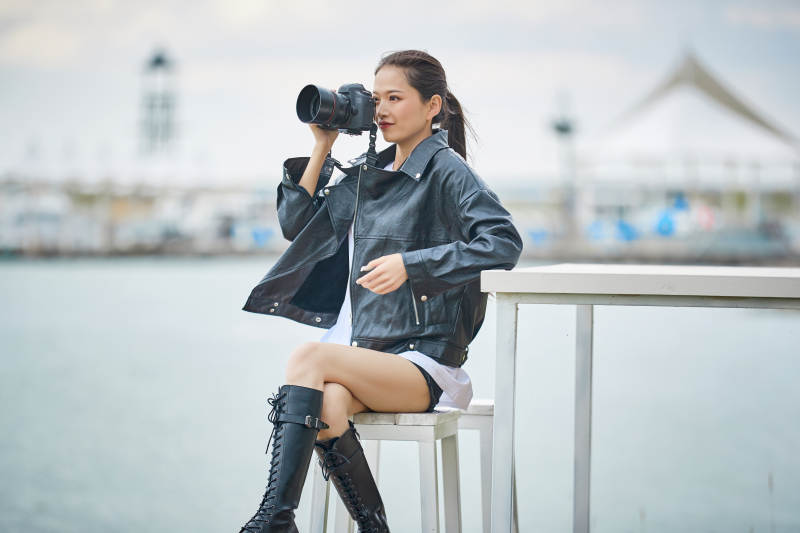 户外湖畔进行拍摄的亚洲青年女性摄影师