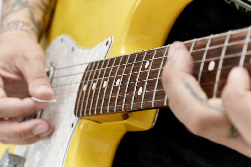 示范演奏摇滚电吉他的亚洲男性乐手人像局部特写