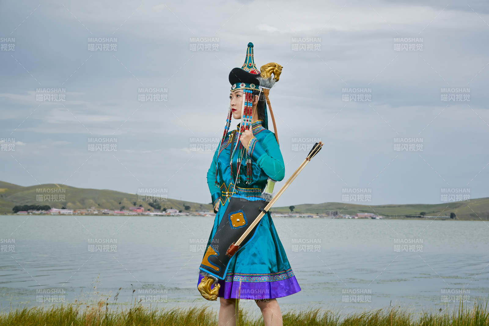 草原湖畔身穿蒙古族饰手持弓箭的蒙族少女