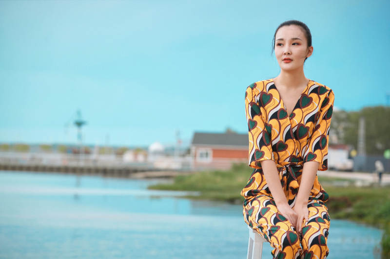 悠闲的坐在美丽湖岸码头的亚洲年轻女性人像