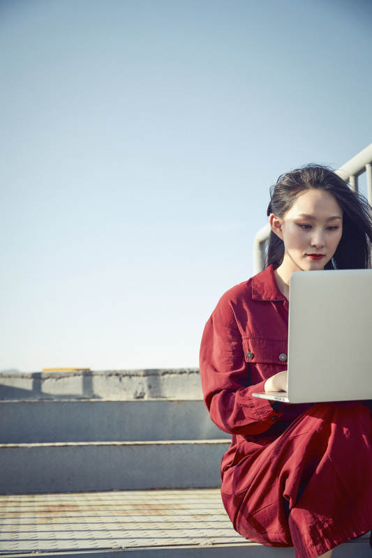 亚洲商务年轻女性在楼顶停机坪使用电脑办公