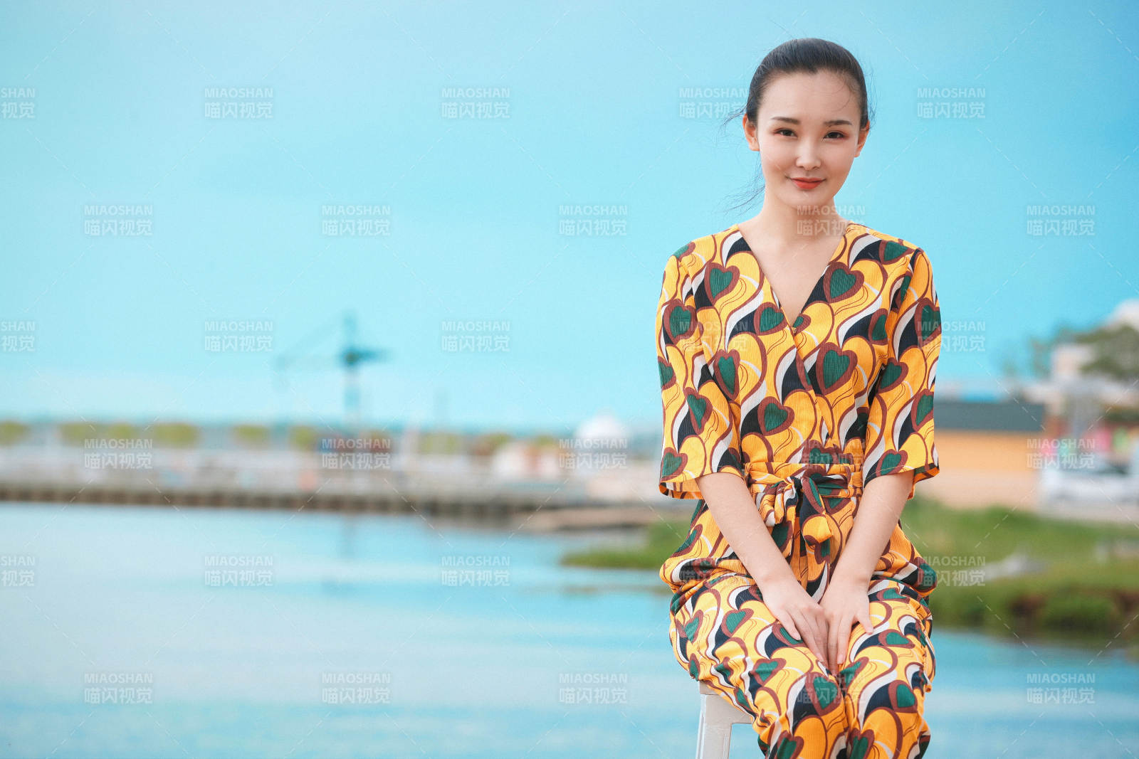 悠闲的坐在美丽湖岸码头的亚洲年轻女性人像