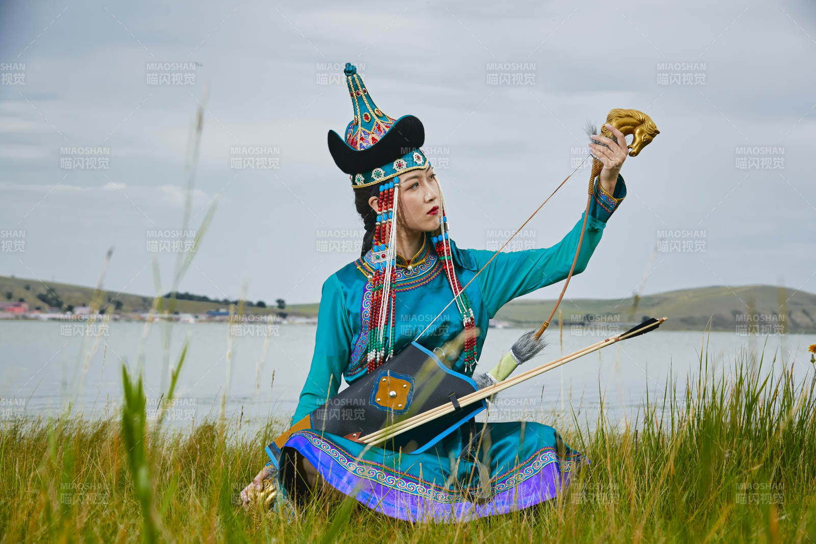 草原湖畔身穿蒙古族飾手持弓箭的蒙族少女