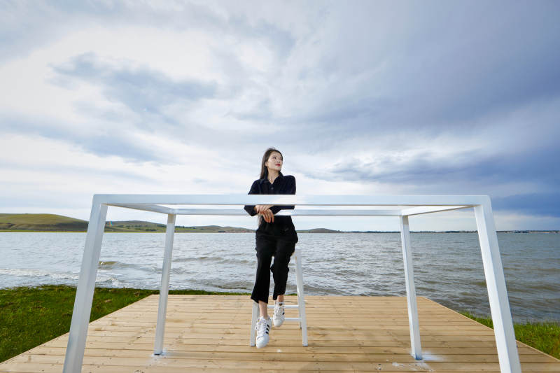 悠闲的坐在美丽湖岸码头的长发少女