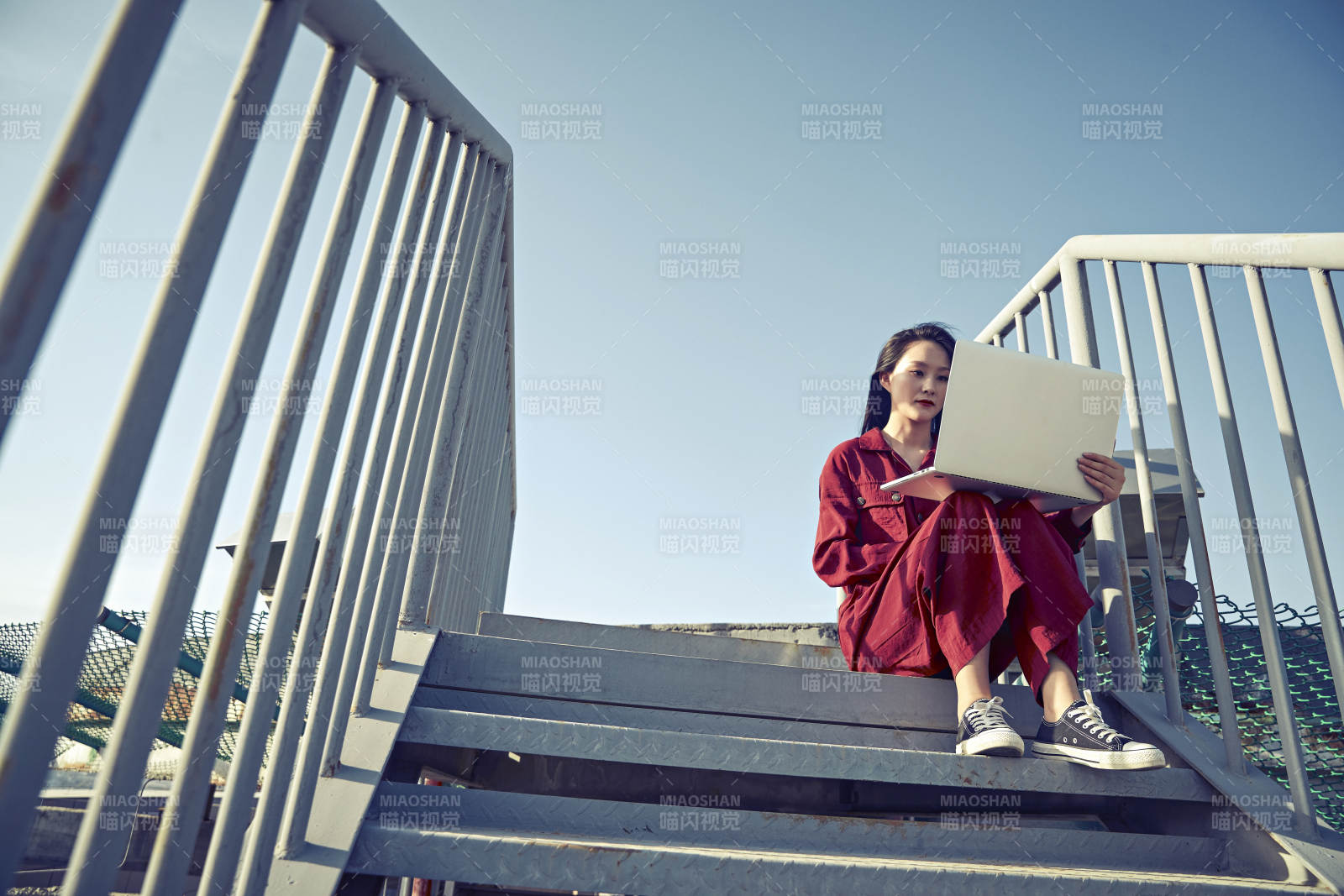 亞洲商務(wù)年輕女性在樓頂停機(jī)坪使用電腦辦公