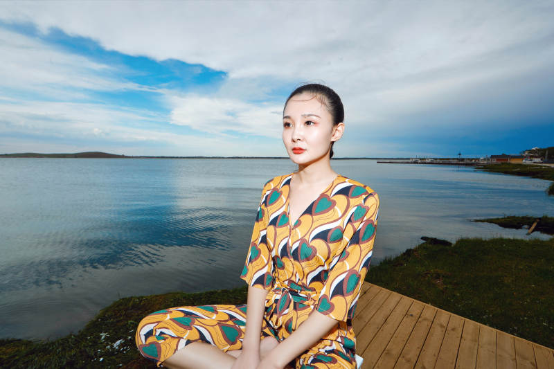 悠闲的坐在美丽湖岸码头的亚洲年轻女性人像