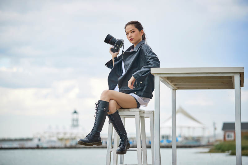 户外湖畔进行拍摄的亚洲青年女性摄影师