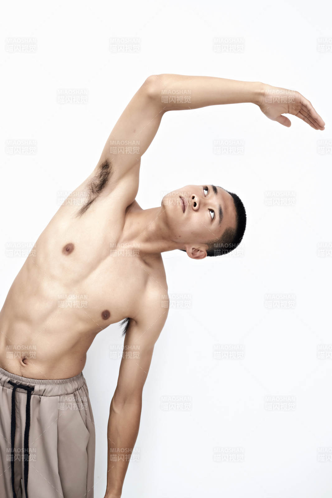 白色背景下展示健身预备拉伸动作的亚洲男性