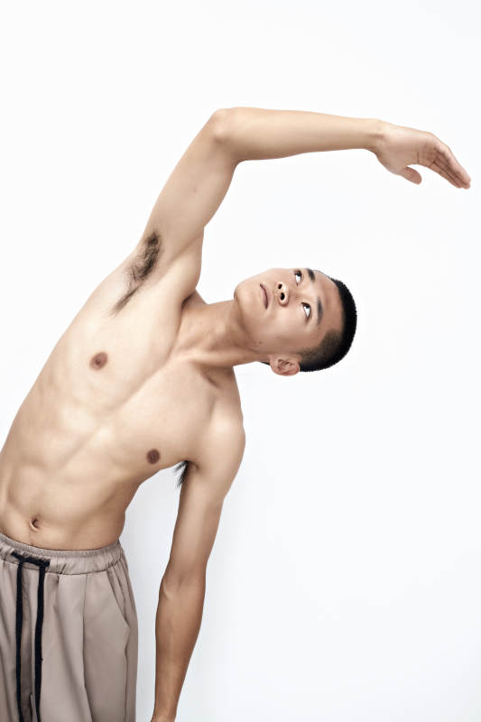 白色背景下展示健身预备拉伸动作的亚洲男性