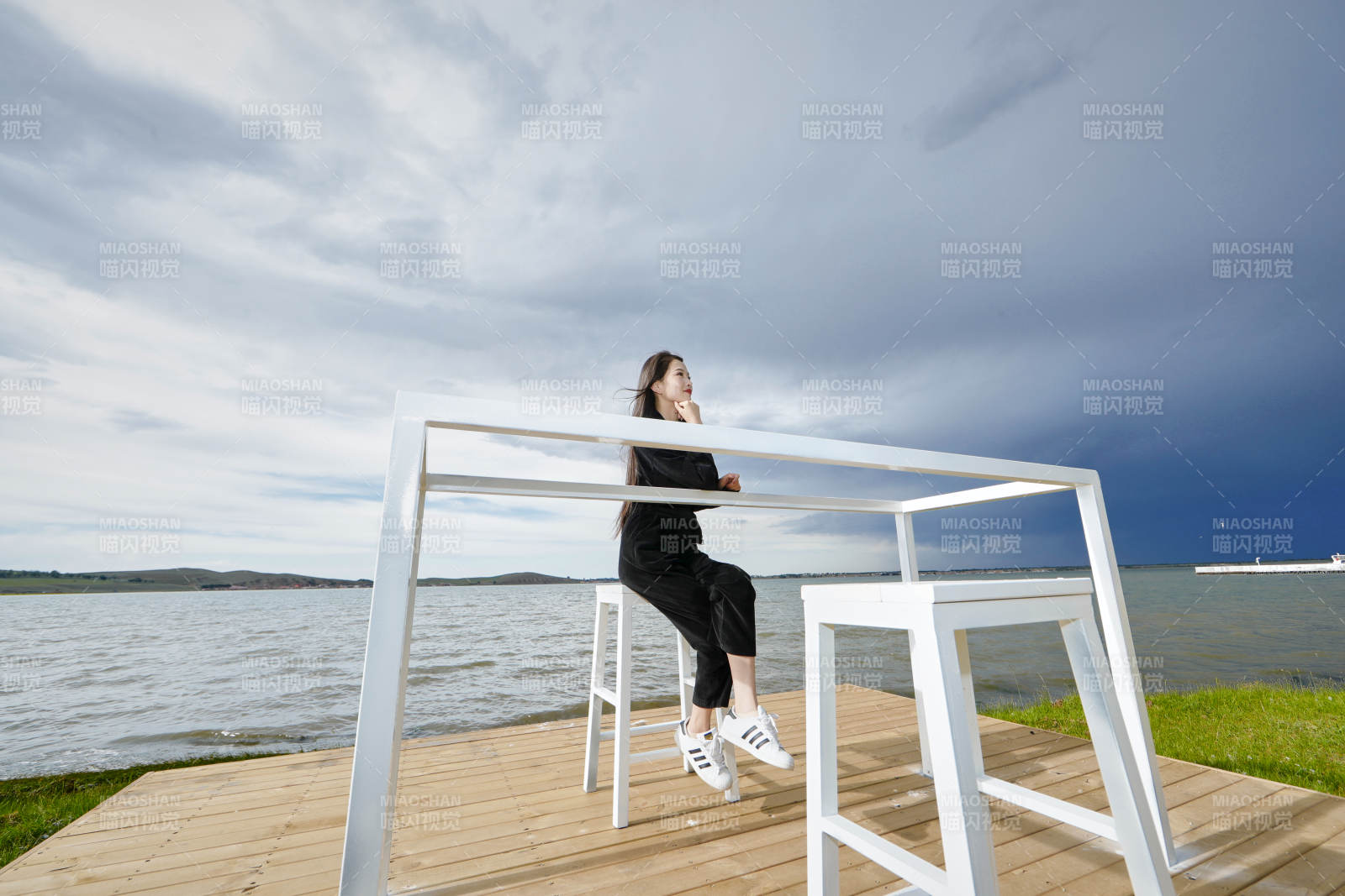 悠閑的坐在美麗湖岸碼頭的長發少女
