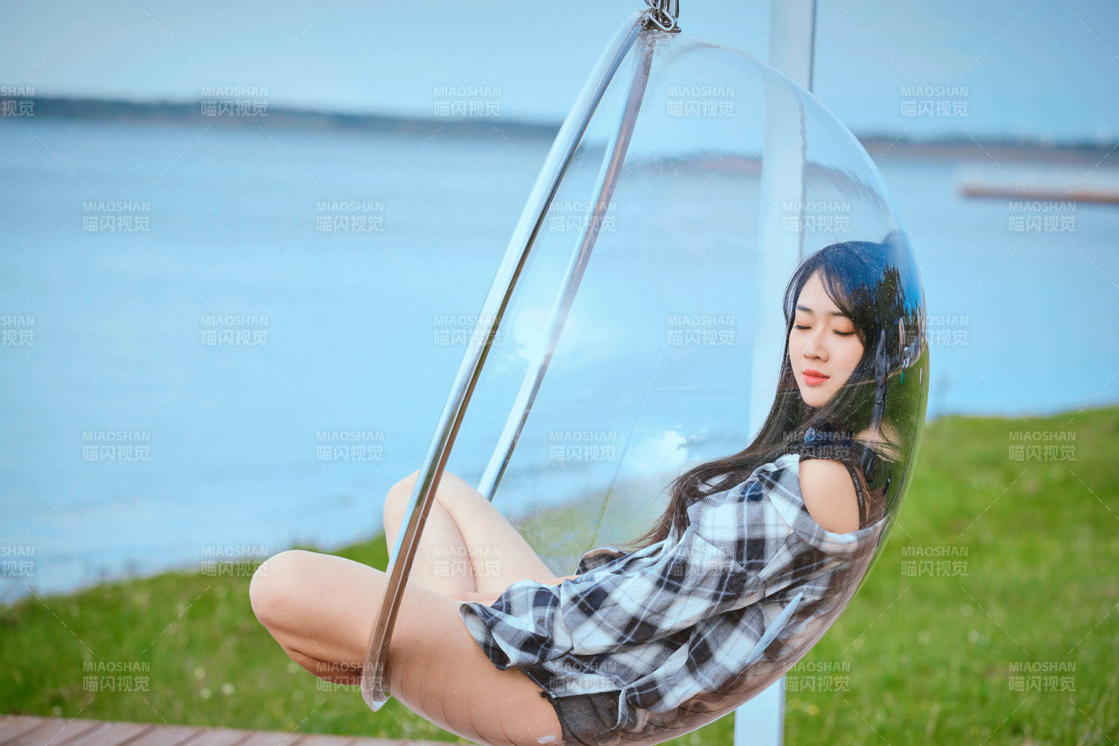 草原湖畔坐在透明秋千里的亞洲年輕女性人像