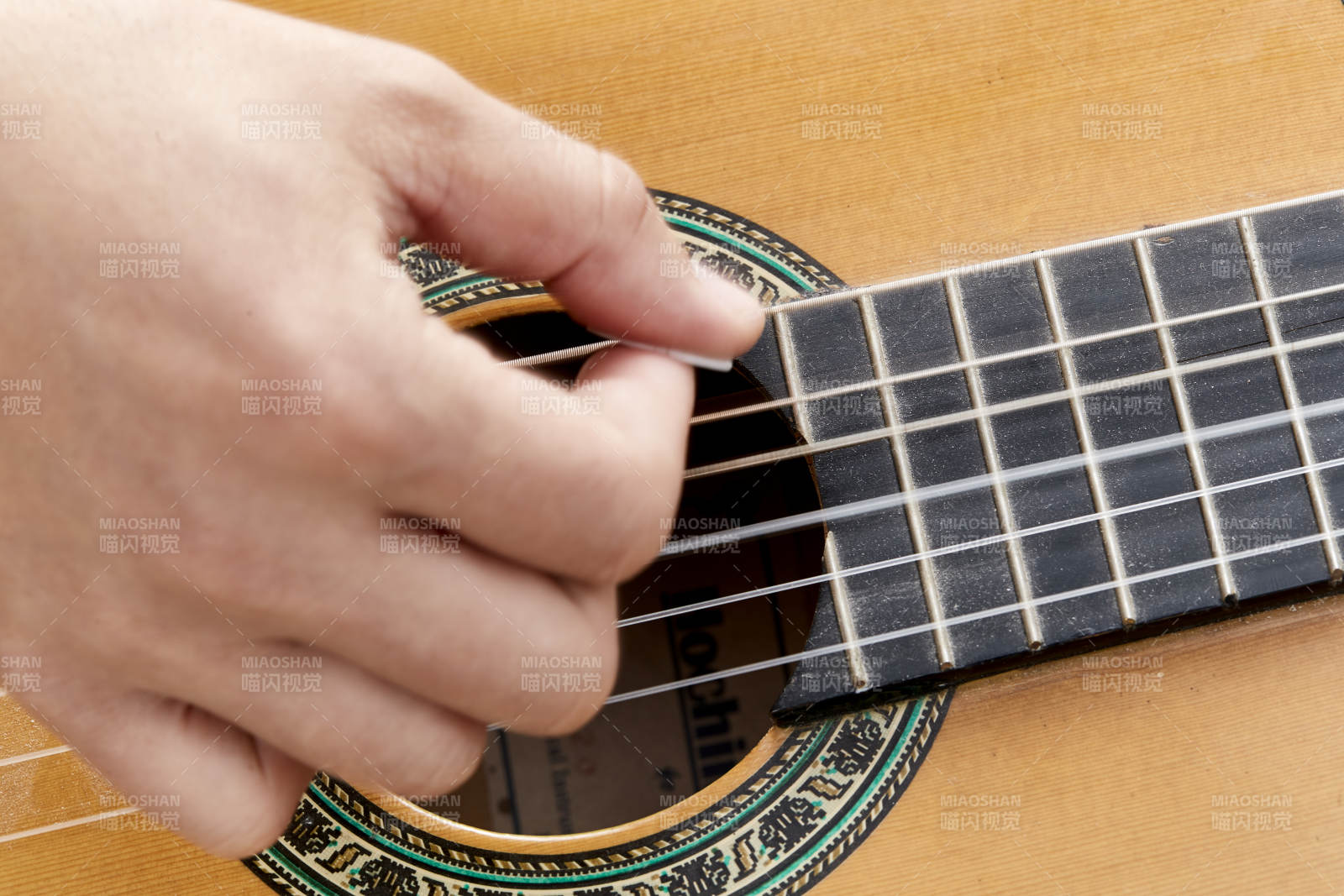 示范演奏古典吉他的亞洲男性樂手人像局部特寫