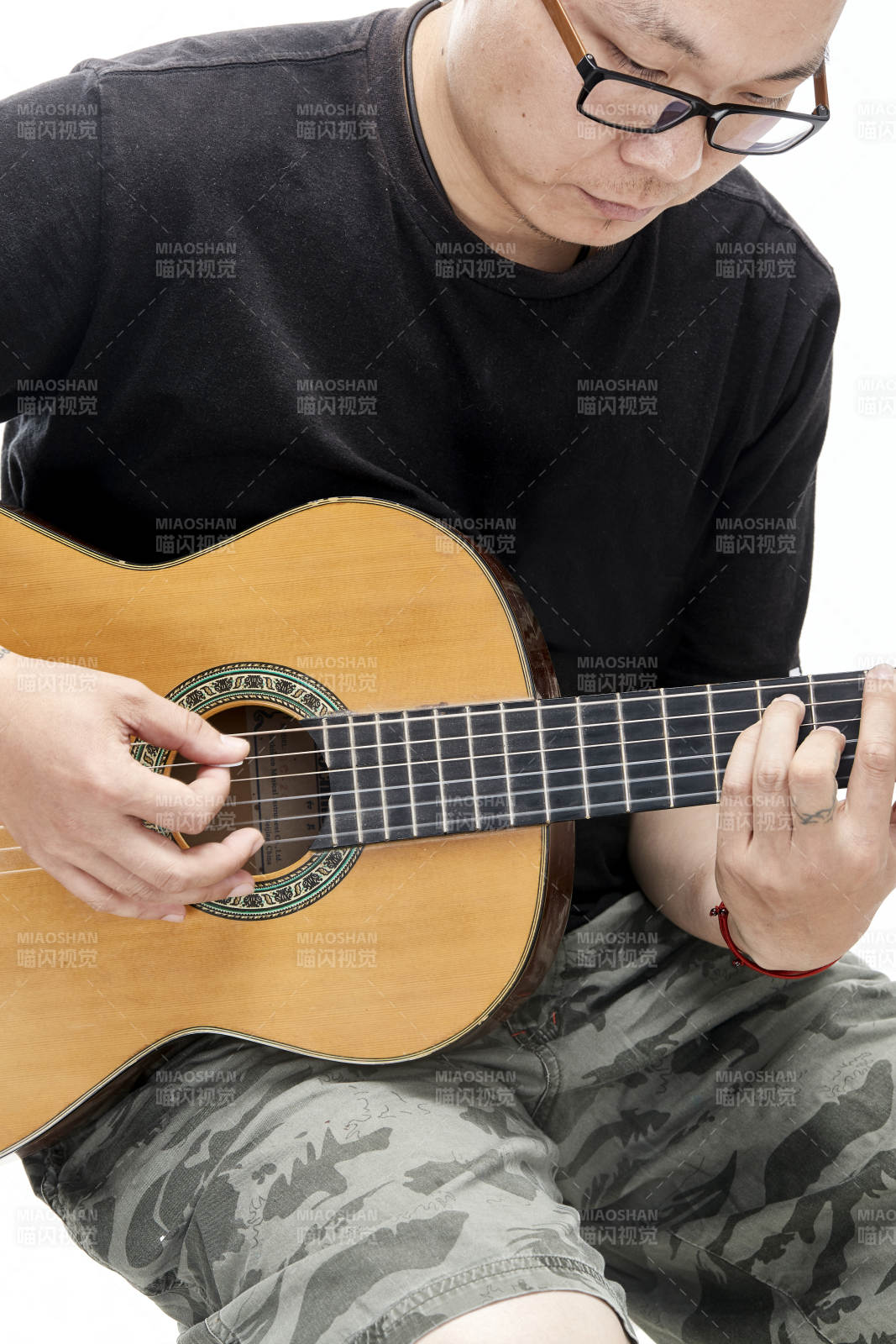 示范演奏古典吉他的亞洲男性樂手人像局部特寫