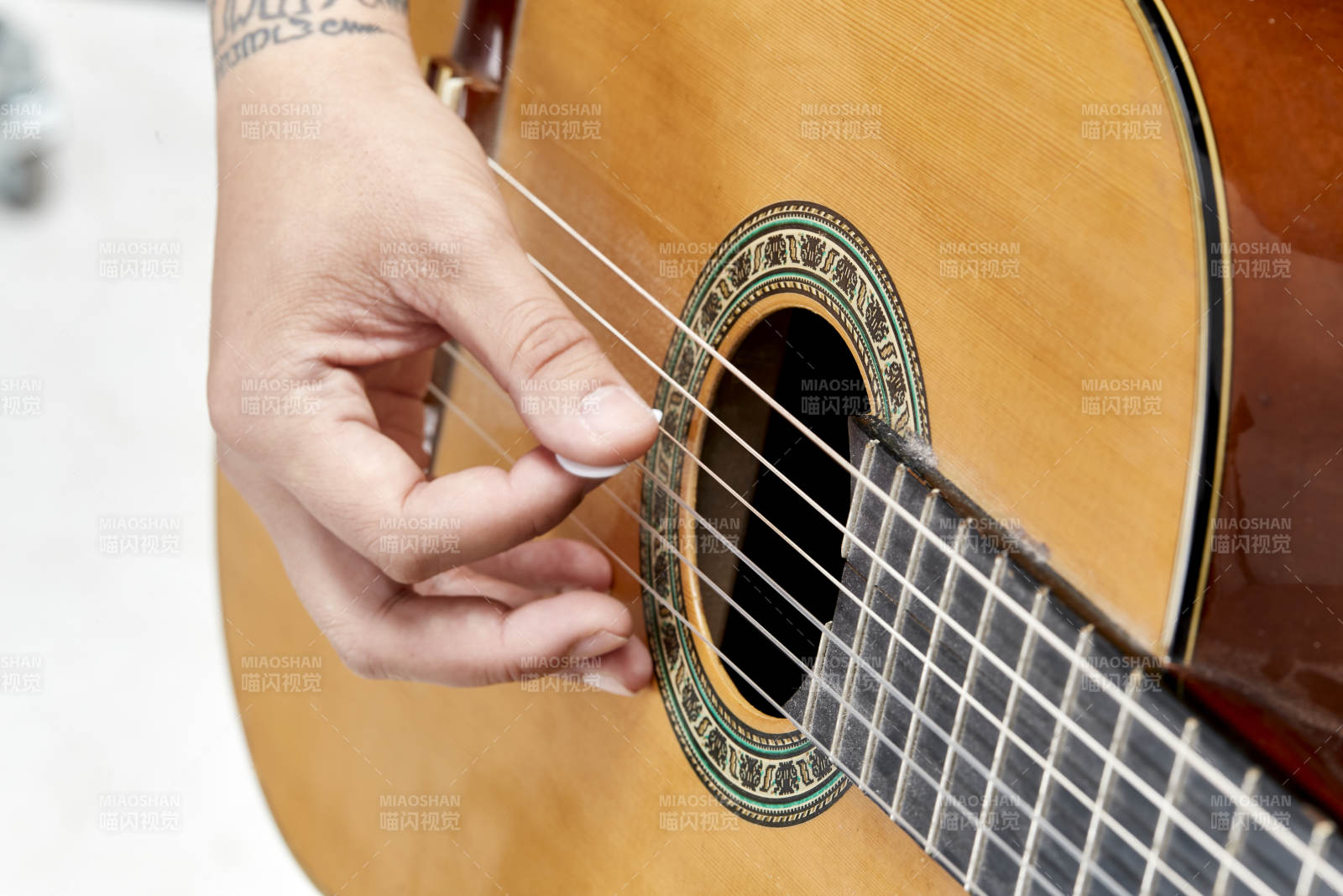 示范演奏古典吉他的亚洲男性乐手人像局部特写