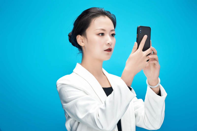 身穿西服拿着手机与文件夹的亚洲商务女士