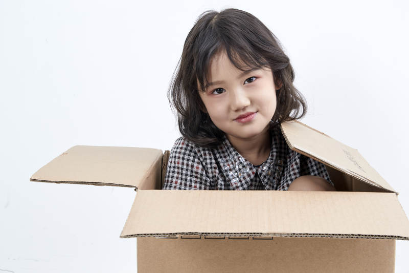 躲在纸箱中玩耍的调皮可爱亚洲小女孩儿童