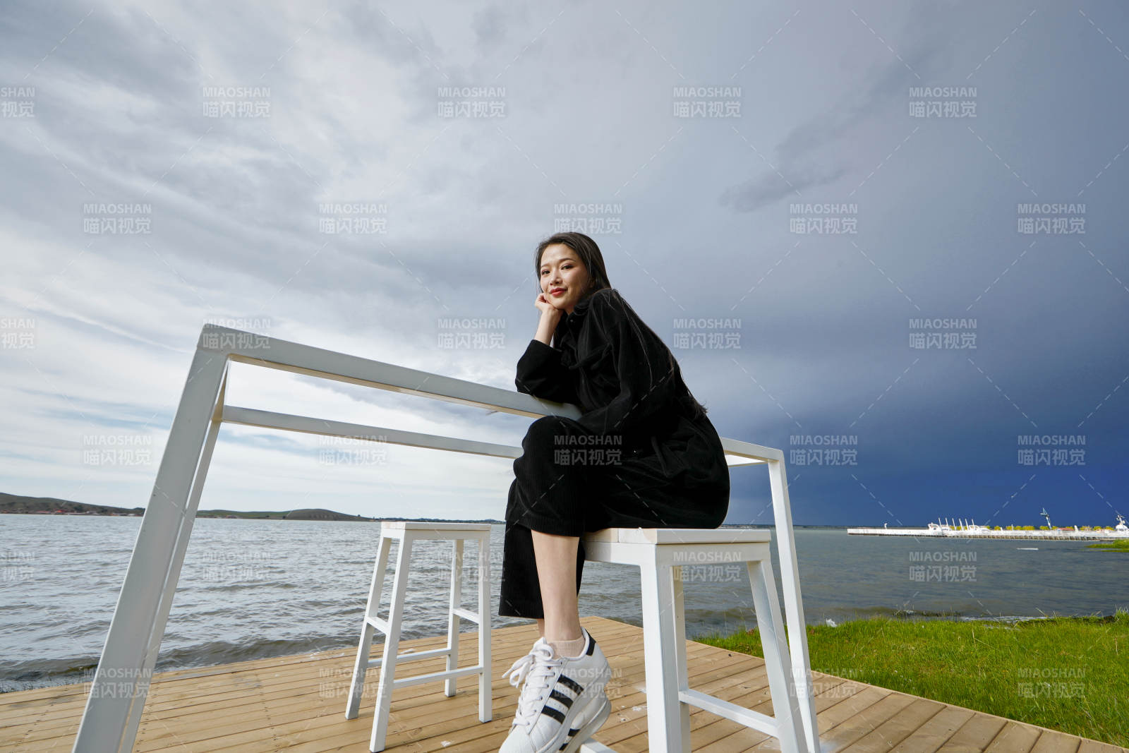 悠閑的坐在美麗湖岸碼頭的長發(fā)少女