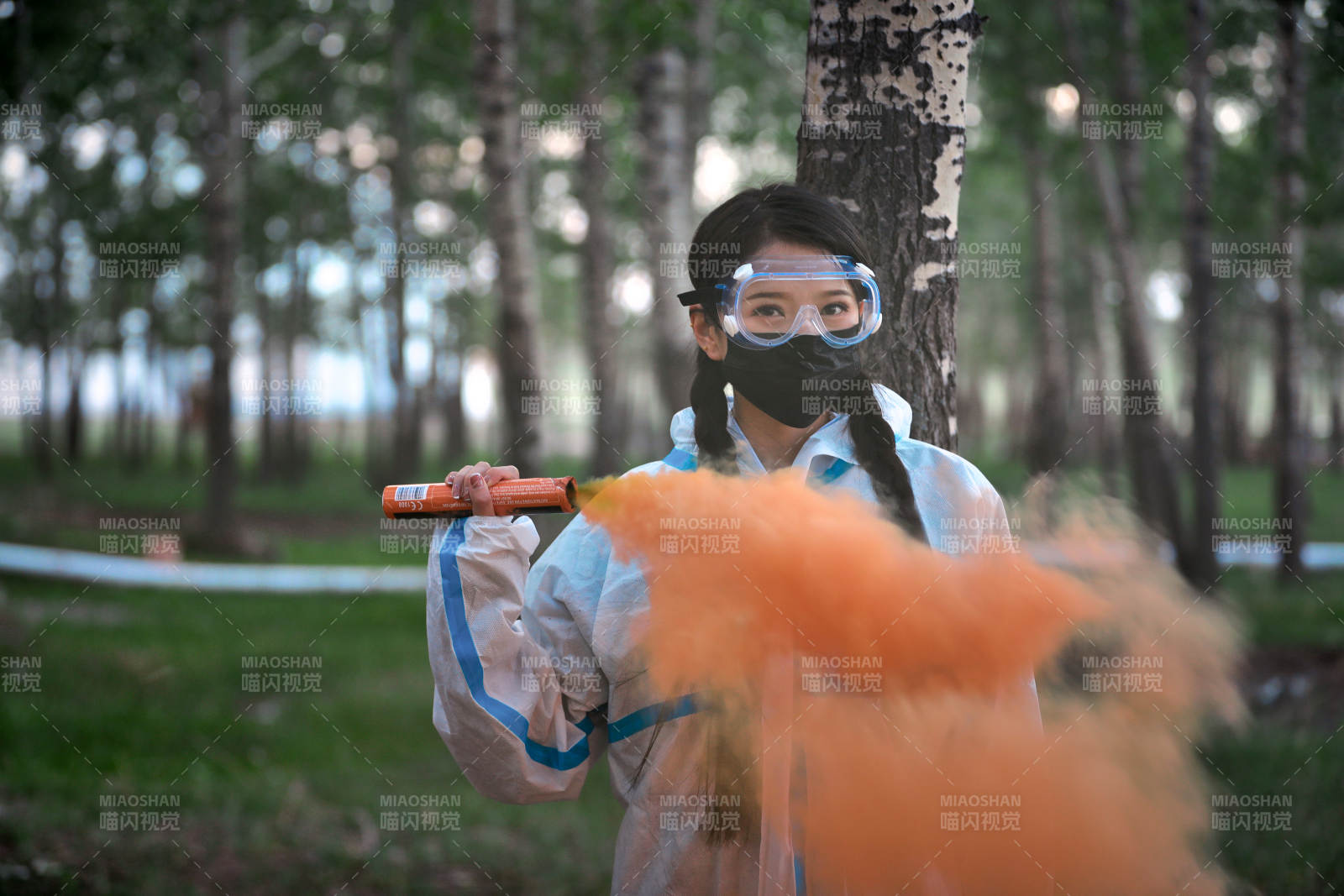 手执彩烟身穿防护服装的女性医疗人员
