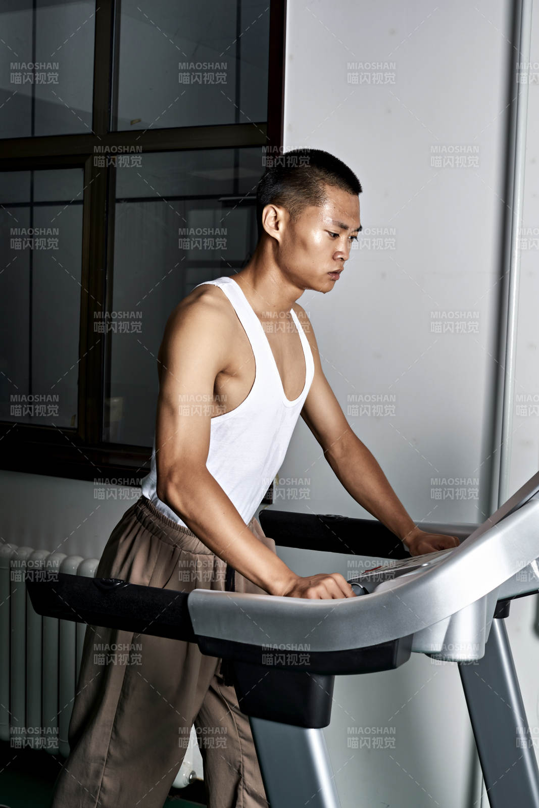 在室內(nèi)用跑步機(jī)進(jìn)行鍛煉的亞洲健身男士形象