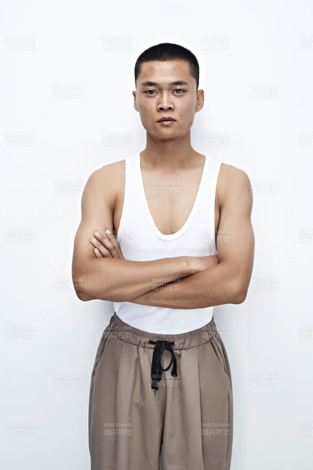 白色背景下展示健身預備拉伸動作的亞洲男性