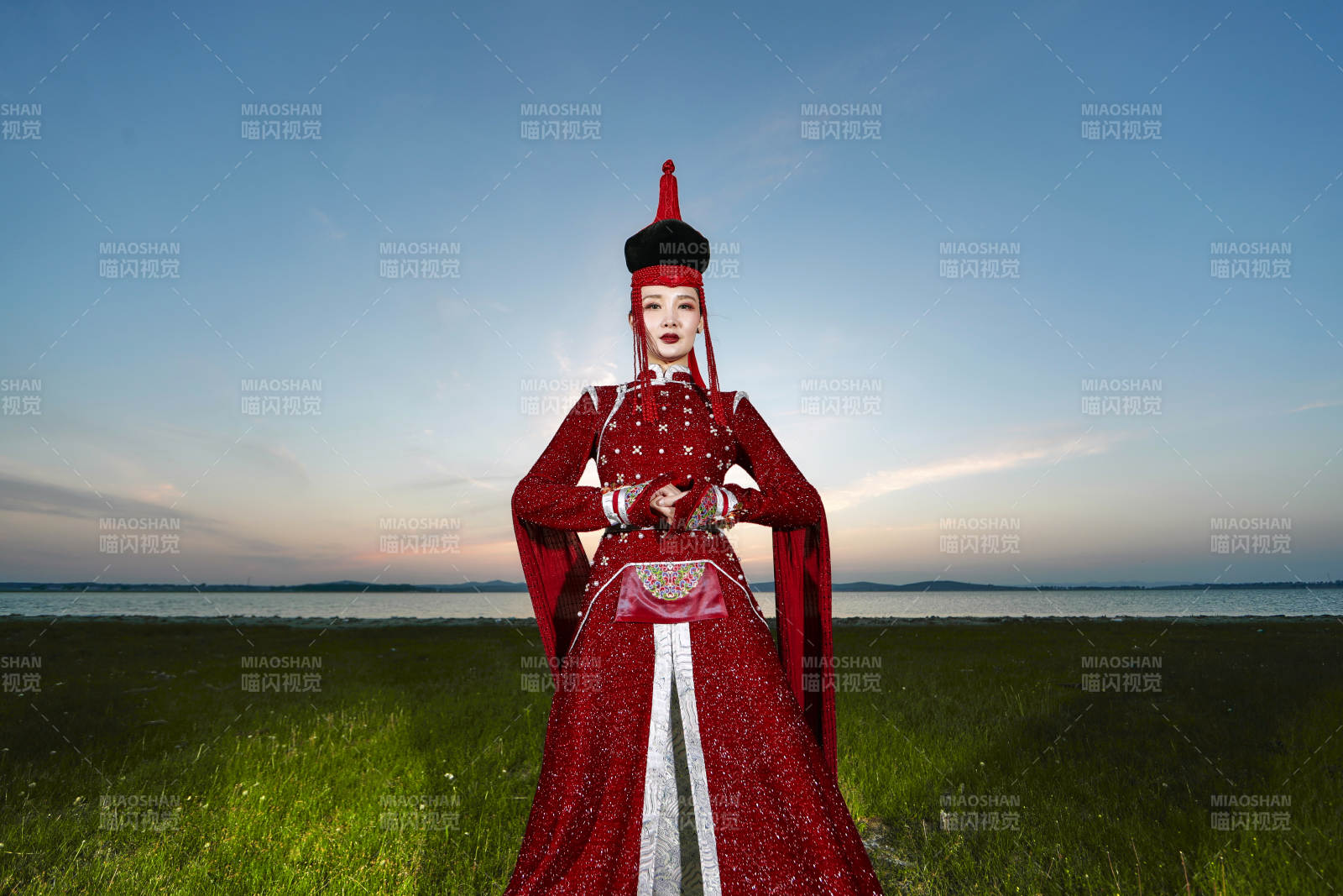 晚霞的草原湖畔穿蒙古族傳統服飾的年輕女性