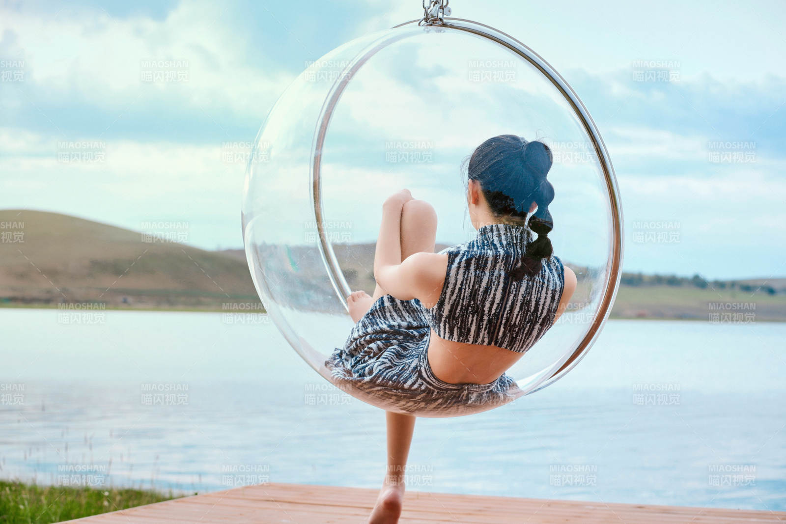 草原湖畔坐在透明秋千里的亞洲年輕女性人像