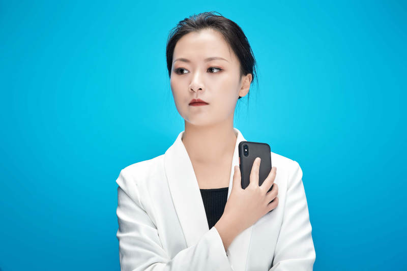 身穿西服拿着手机与文件夹的亚洲商务女士