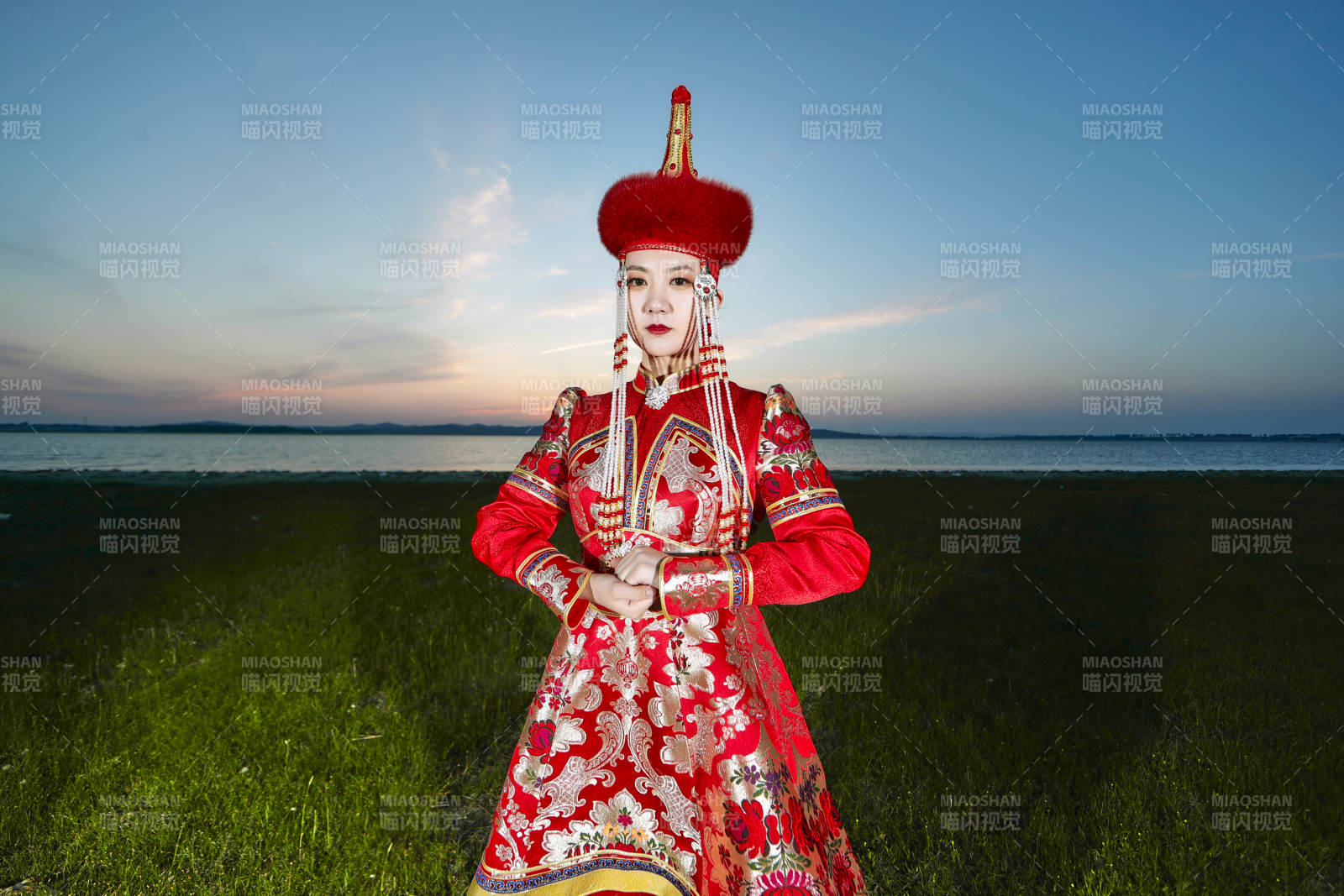 晚霞的草原湖畔穿蒙古族傳統服飾的年輕女性