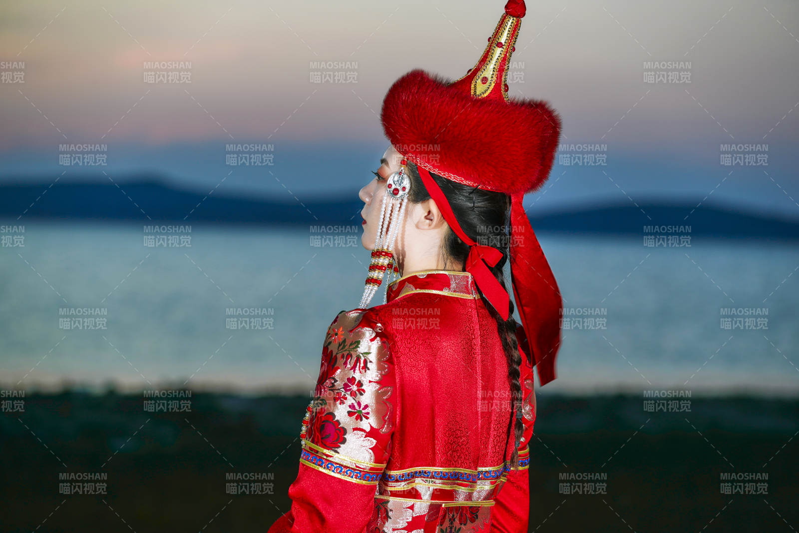 晚霞的草原湖畔穿蒙古族傳統服飾的年輕女性