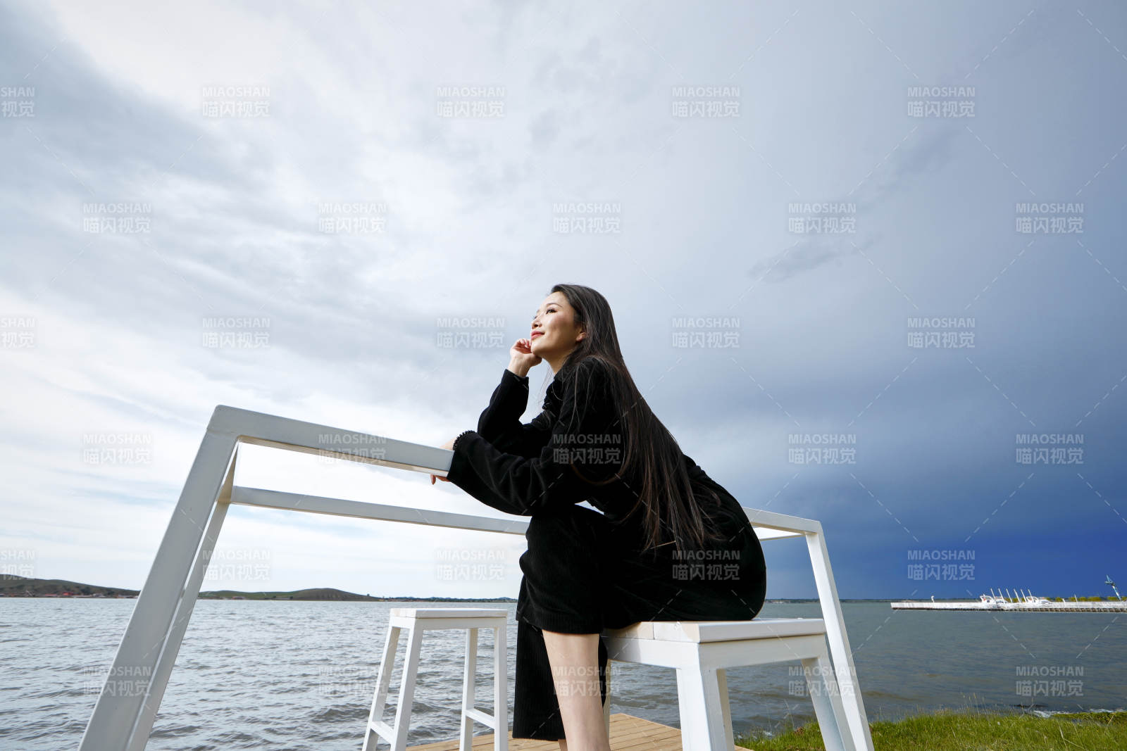悠闲的坐在美丽湖岸码头的长发少女