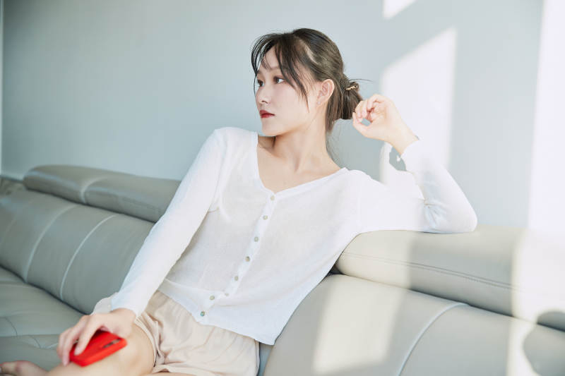 在沙发床上玩手机的年轻亚洲女性