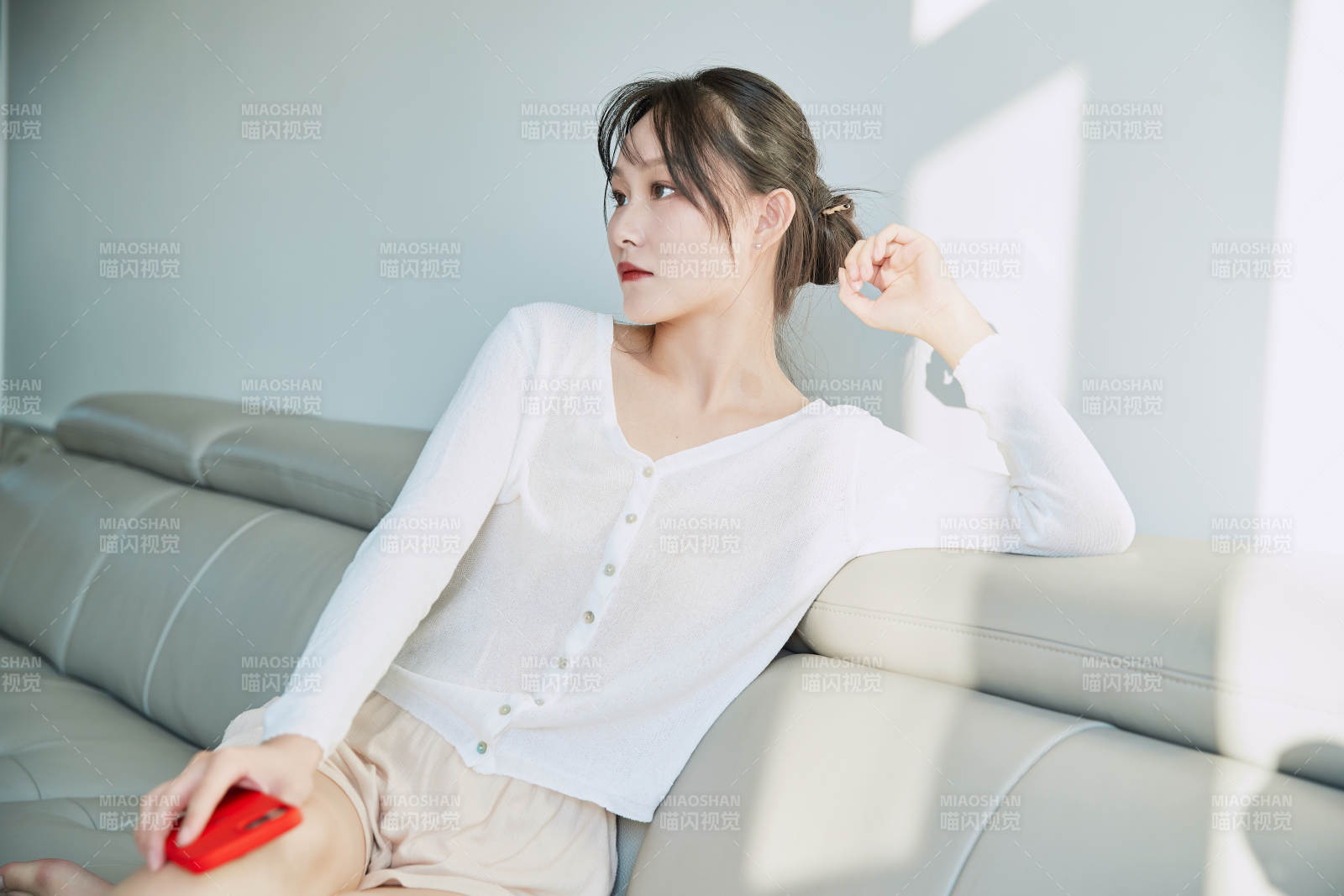 在沙发床上玩手机的年轻亚洲女性