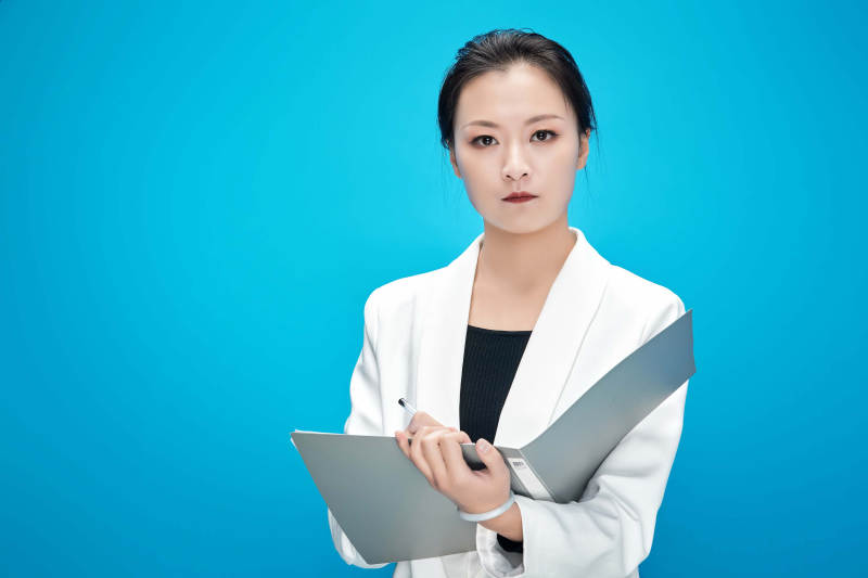 身穿西服拿著手機與文件夾的亞洲商務女士