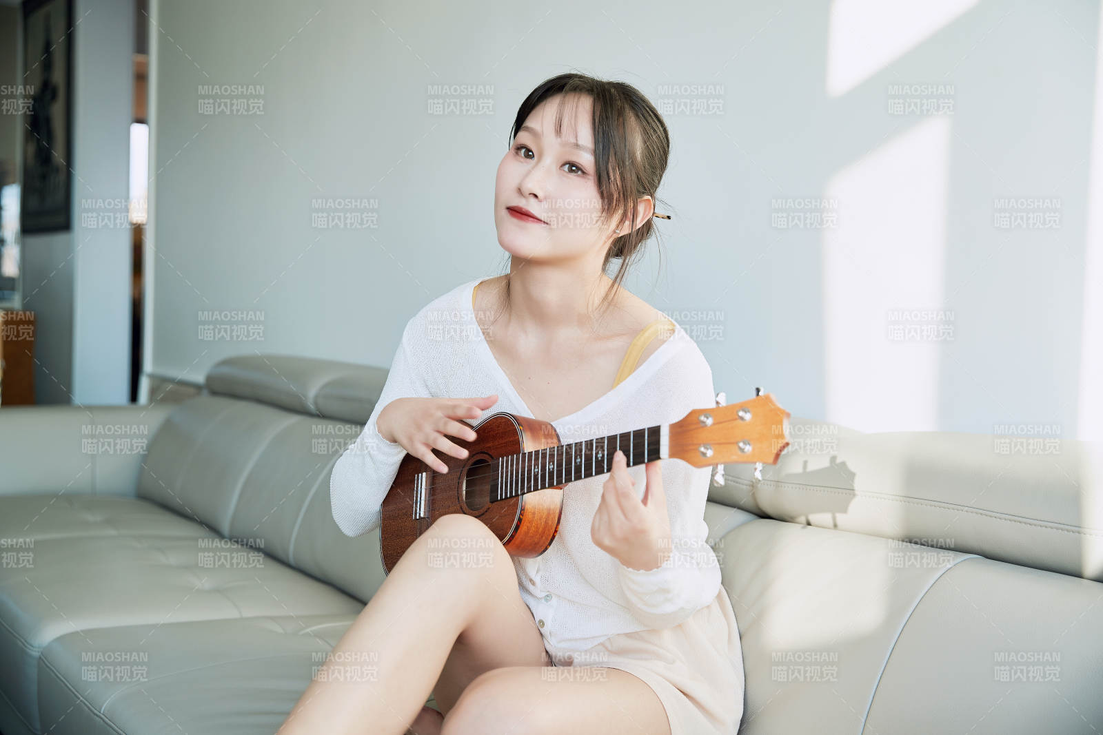 坐在沙發上彈奏尤克里里的少女