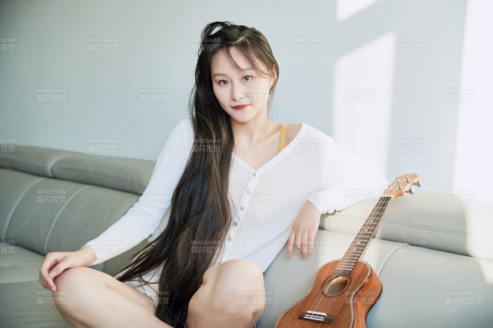 坐在沙發上彈奏尤克里里的少女