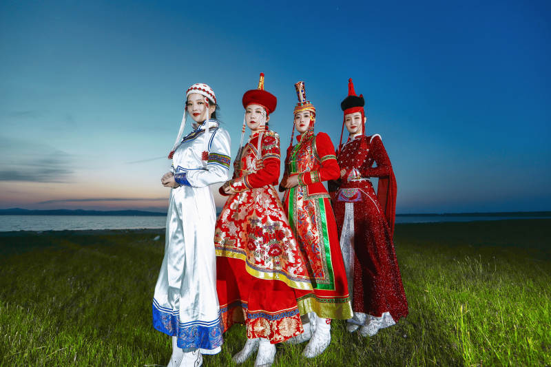 晚霞的草原湖畔穿蒙古族传统服饰的年轻女性