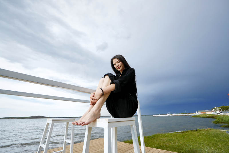 悠闲的坐在美丽湖岸码头的长发少女